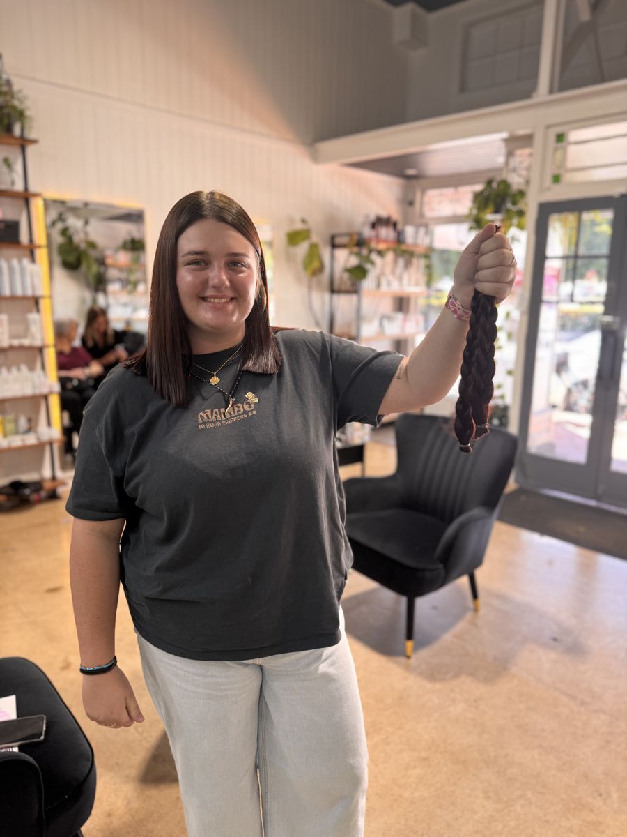 A client holding the plaited ponytail she donated at Winter & Co.