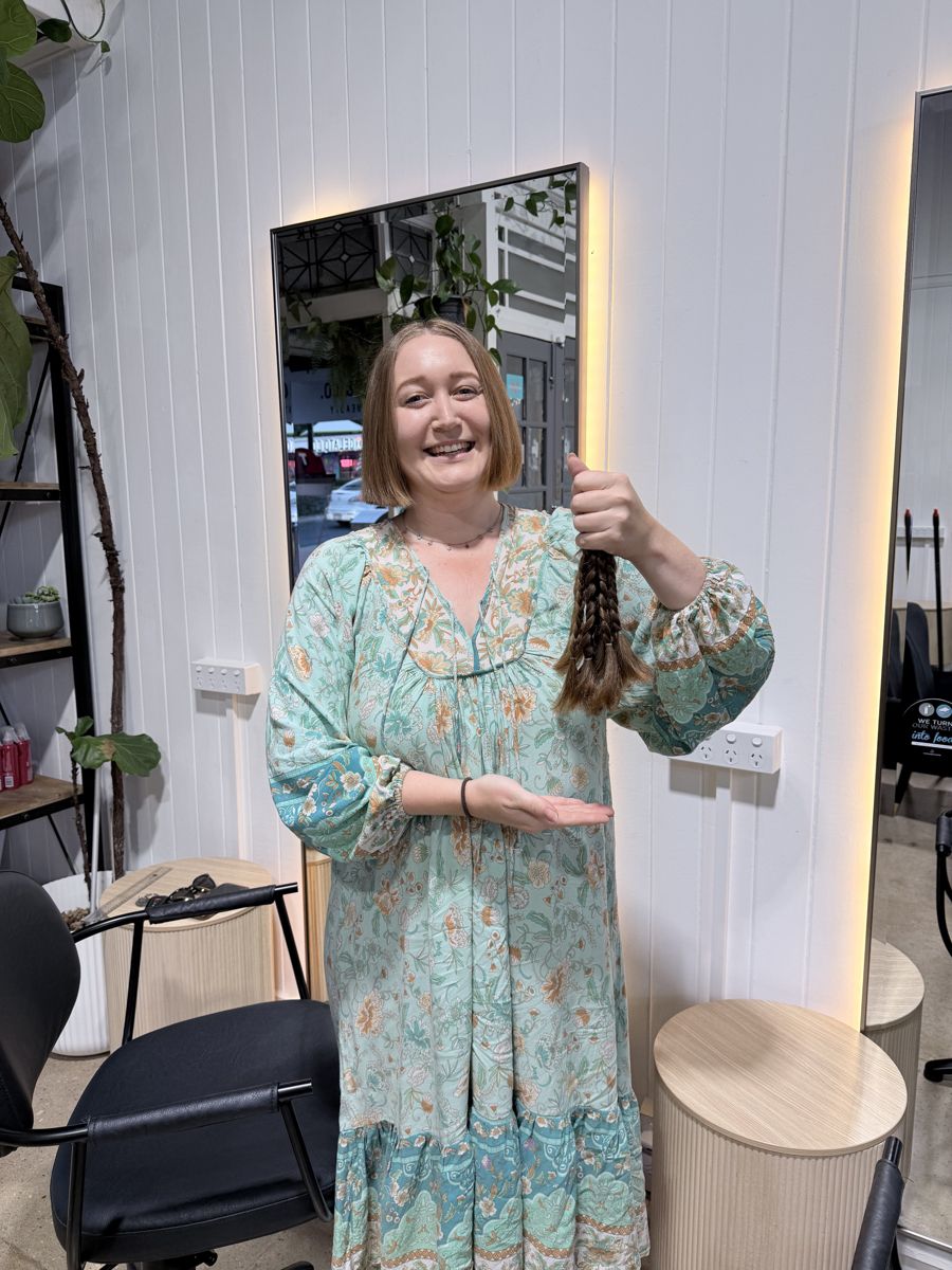 A client holding the plaited ponytail she donated at Winter & Co.